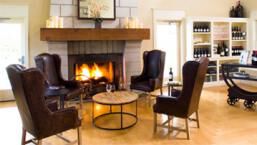 Four person seated tasting next to fireplace in side Arrowood Tasting Room.