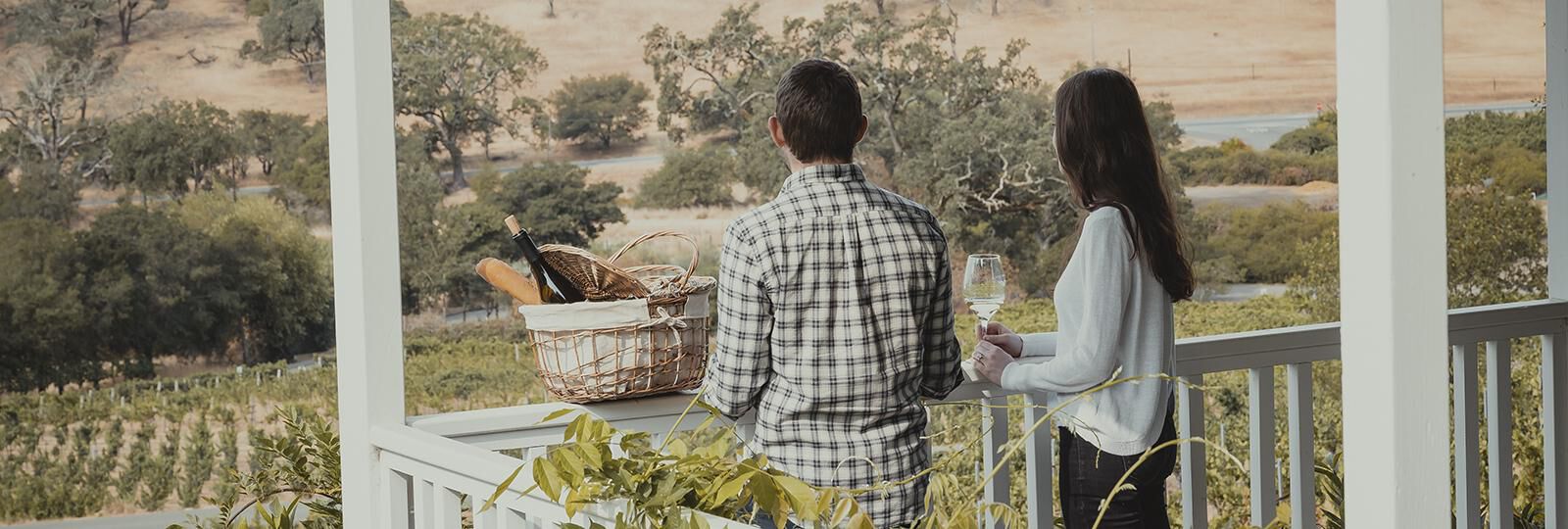 Two people on the Arrowood porch looking out into the vineyard.