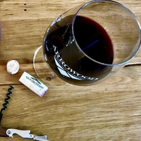 Looking down at a glass of Arrowood Vineyards red wine standing on a wooden counter.